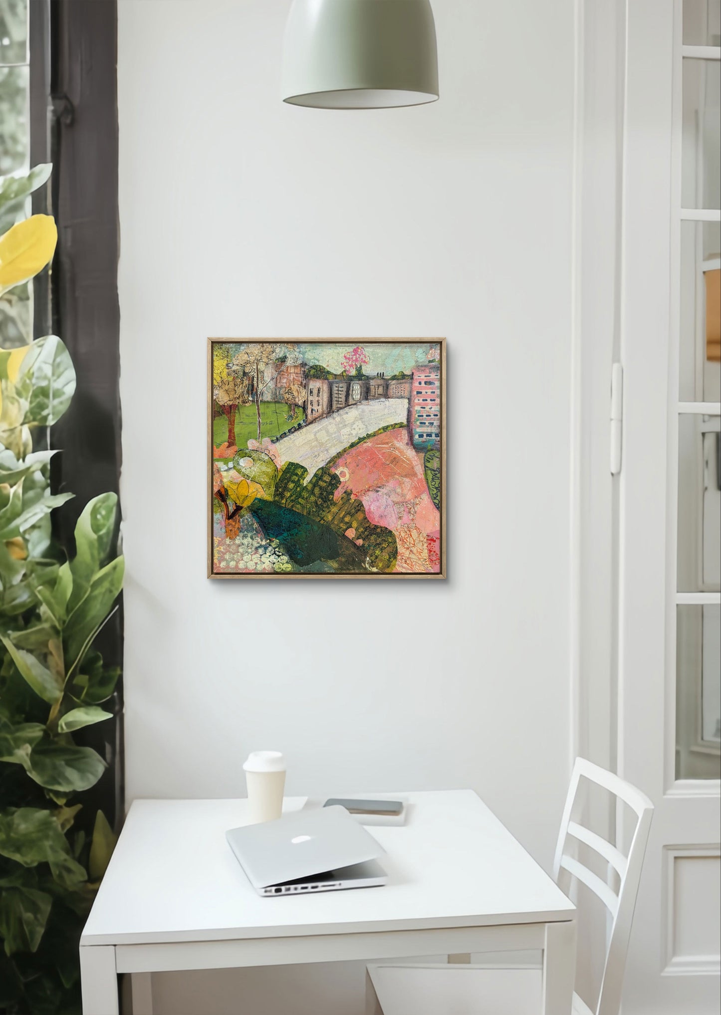 Abstract landscape painting titled The Village on the Hill by Jen Rodger featuring rolling greens and blues with a symbolic village below, representing calm, balance and perspective within the busyness of life. The painting is sitting above a white timber table and chair.