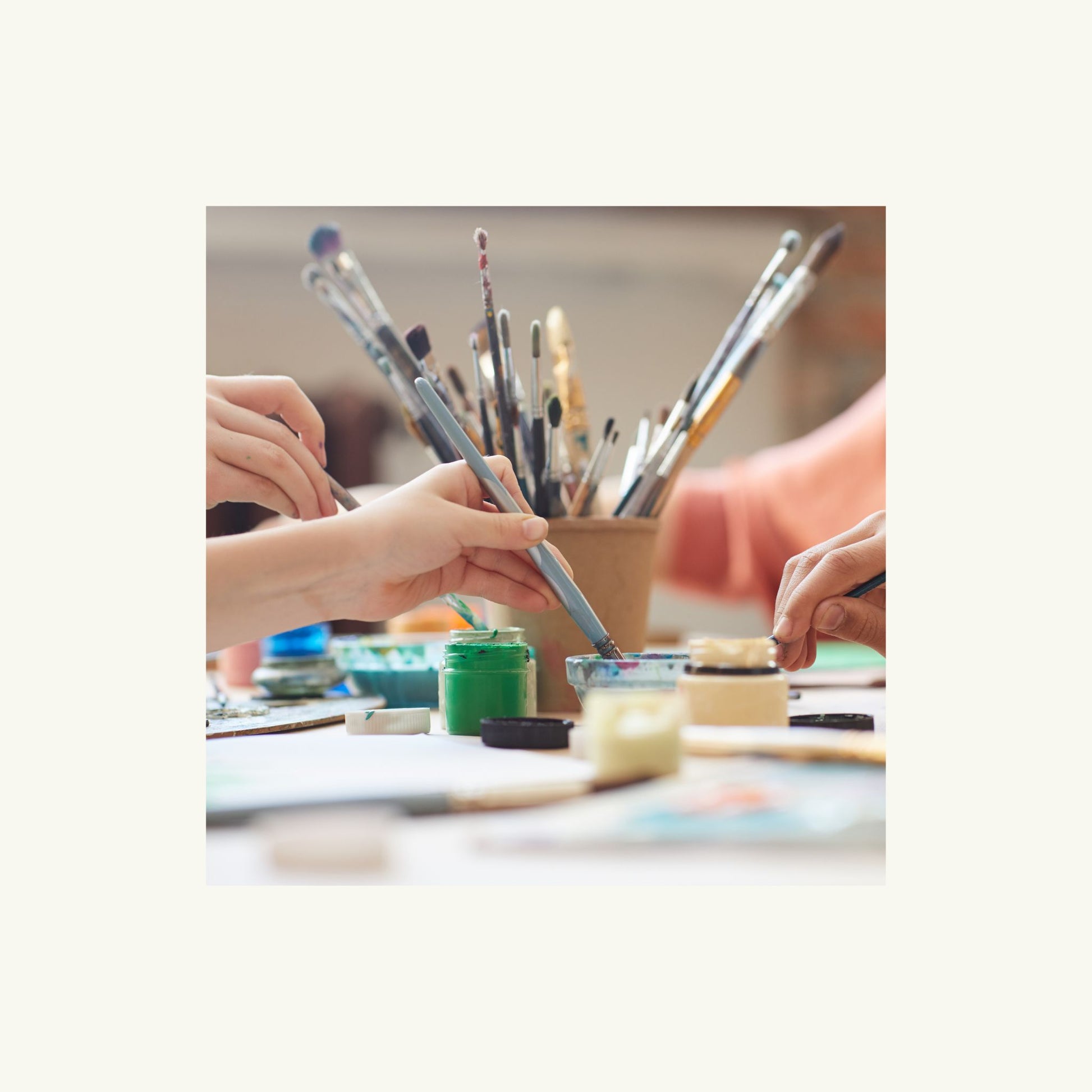 Artistic activity with paintbrushes and containers on a table.