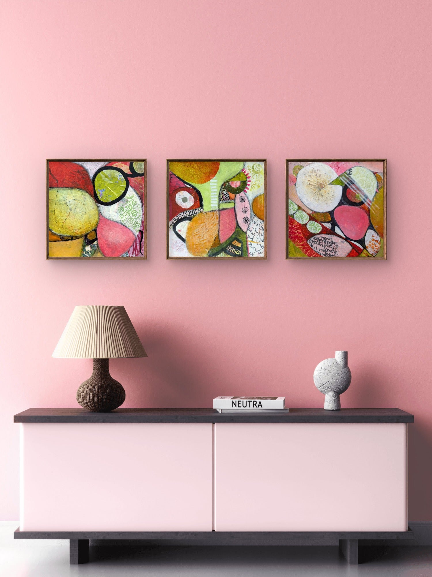 Trio of vibrant abstract artworks by Jen Rodger hanging above a soft pink sideboard in a modern interior.